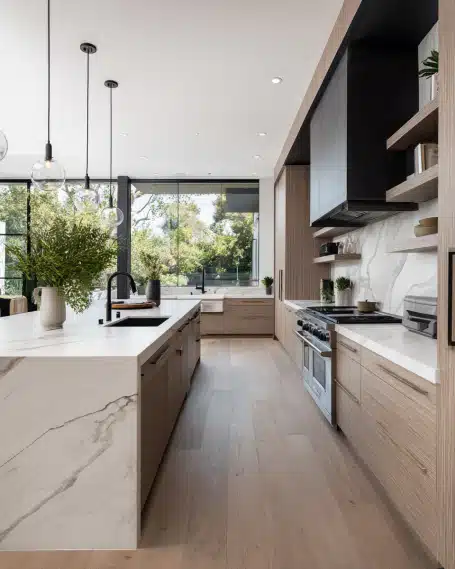 Luxurious modern California kitchen with a marble waterfall island and warm wood cabinetry by a top kitchen makeover company.