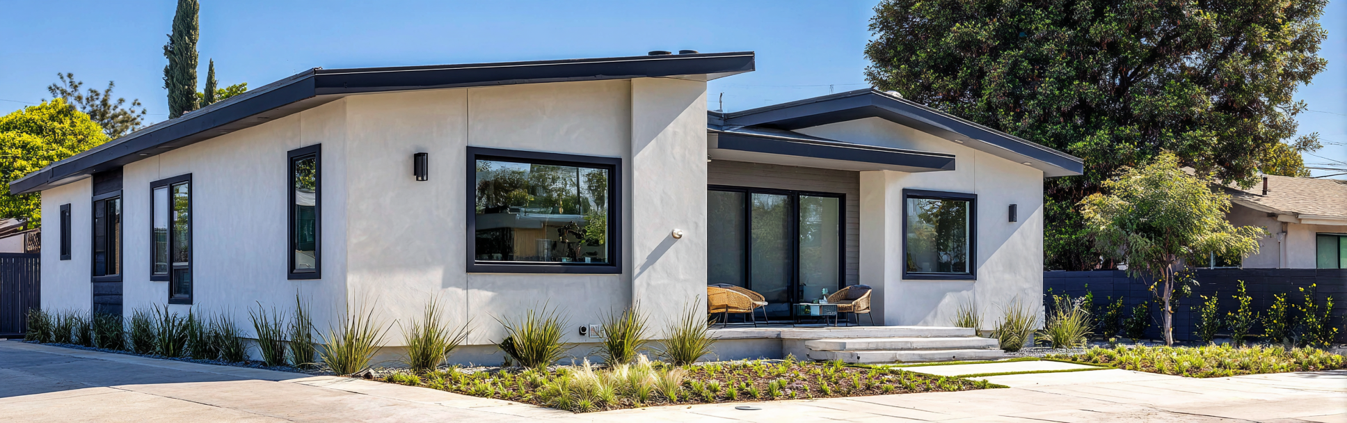 Exterior of a modern ADU in Cypress with light stucco walls and dark-framed windows under bright daylight.
