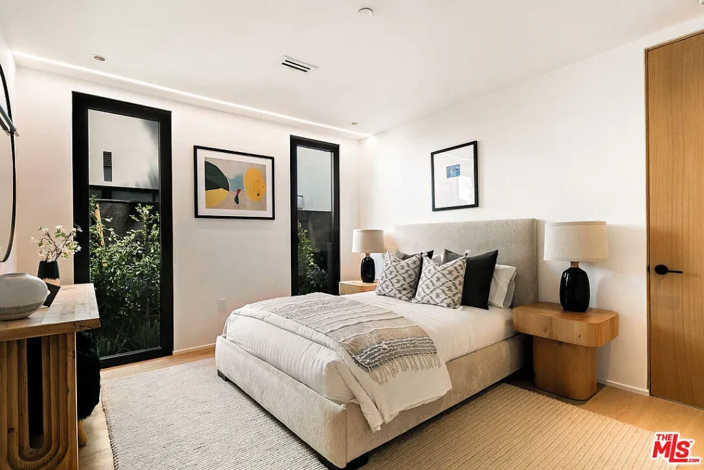 Contemporary bedroom interior at 2202 California Ave in Santa Monica featuring a modern upholstered bed, black framed windows, wood accents and minimalist decor