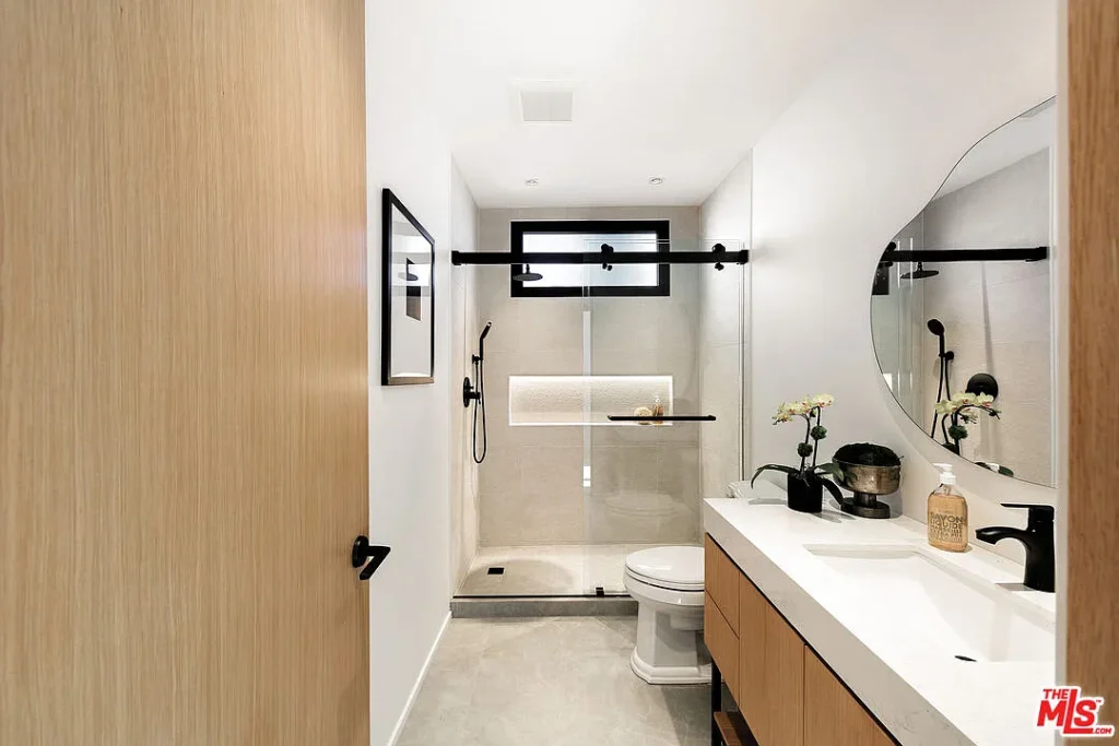 Modern bathroom shower at 2202 California Ave in Santa Monica featuring a frameless glass enclosure, floating vanity, black fixtures and minimalist design