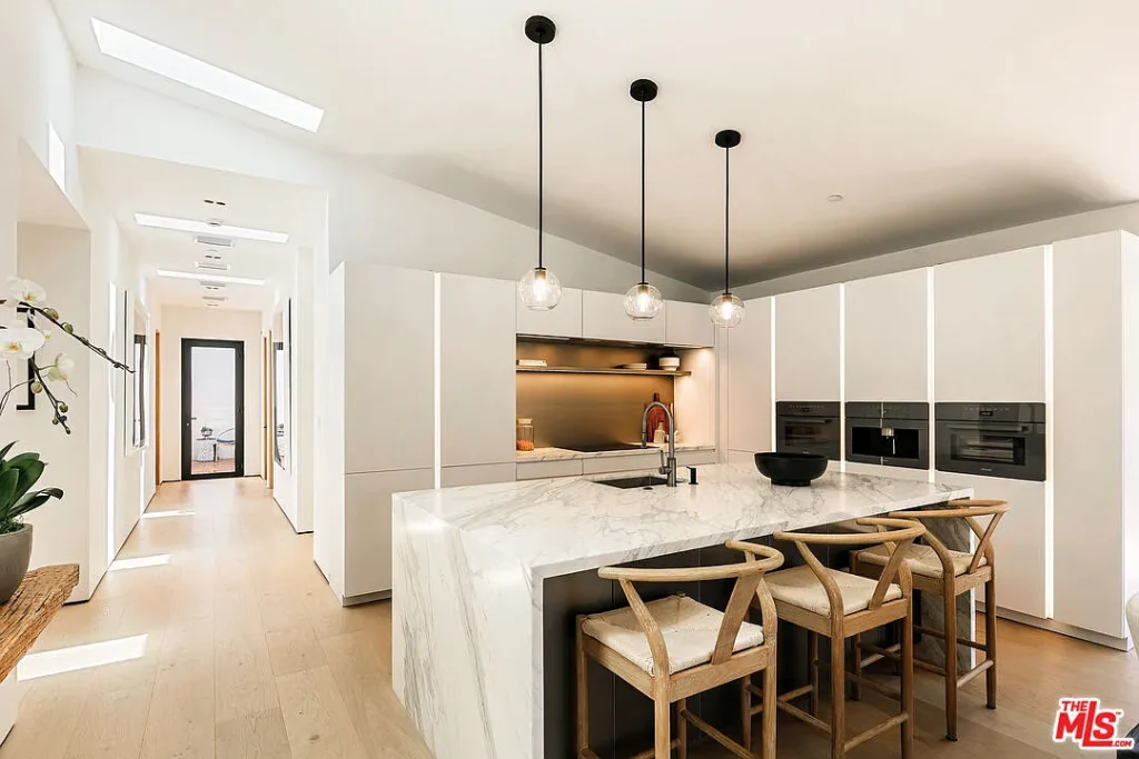 Modern kitchen interior at 2202 California Ave in Santa Monica featuring a marble island, white cabinetry, pendant lighting and contemporary design finishes