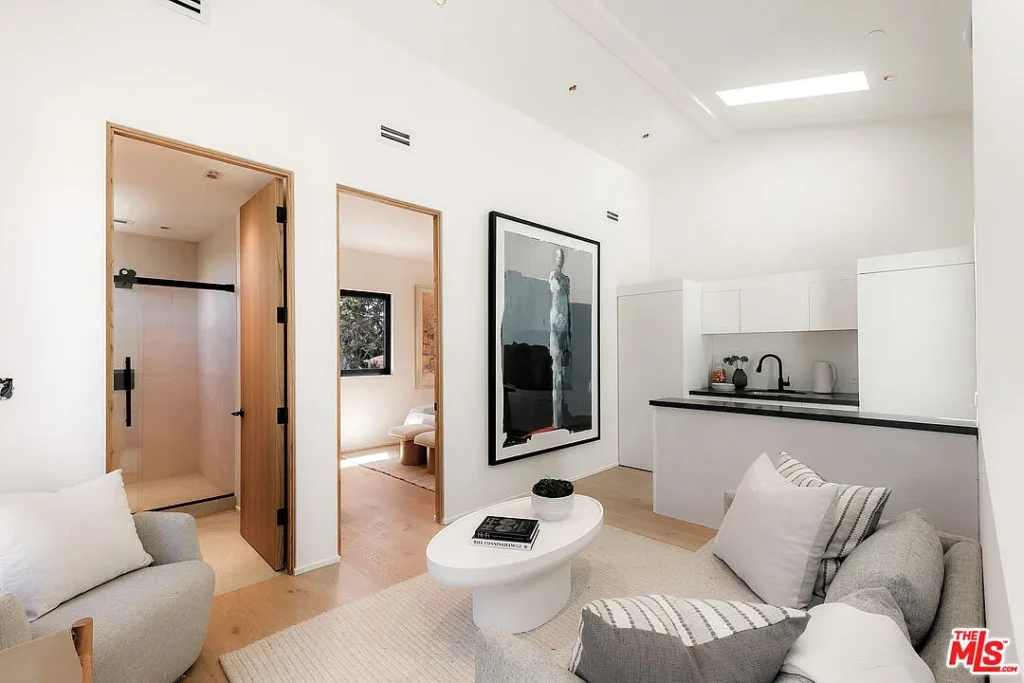 Modern living room interior at 2202 California Ave in Santa Monica featuring minimalist furniture, open kitchen design, skylight, artwork and contemporary finishes