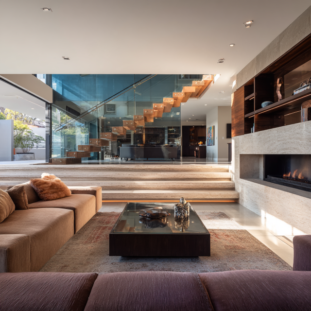 Renovated 1970s split-level family room featuring a spacious modular sofa, modern fireplace, smoked oak finishes and short staircase connecting two living levels.